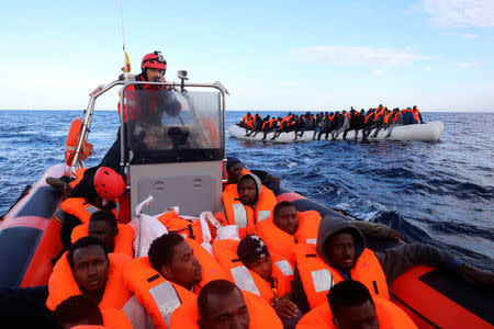 Sub-Saharan migrants are seen aboard an overcrowded raft as others are seen onboard a rescue boat. REUTERS/Giorgos Moutafis