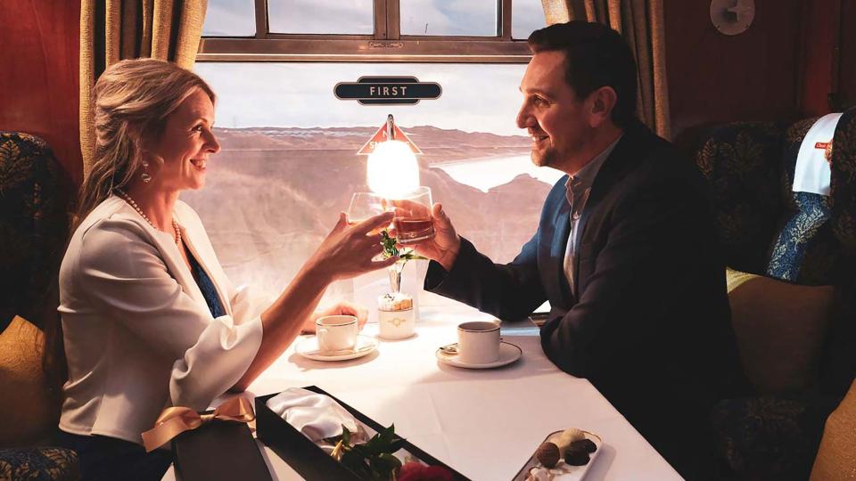 Man and woman raising glasses on luxury train