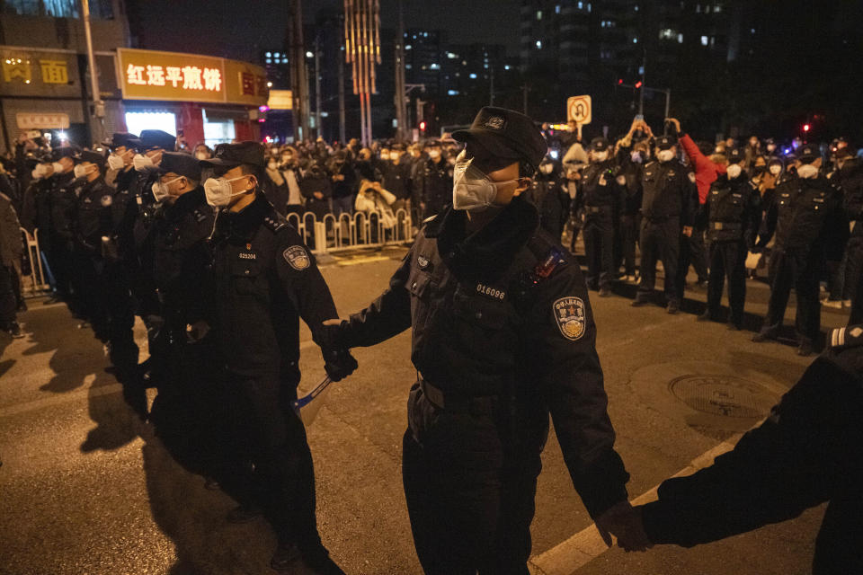 FILE - Chinese policemen form a line to stop protesters marching against anti-virus measures in Beijing, Nov. 27, 2022. China's sudden reopening after two years holding to a "zero-COVID" strategy left older people vulnerable and hospitals and pharmacies unprepared during the season when the virus spreads most easily, leading to many avoidable deaths, The Associated Press has found. (AP Photo/Ng Han Guan, File)