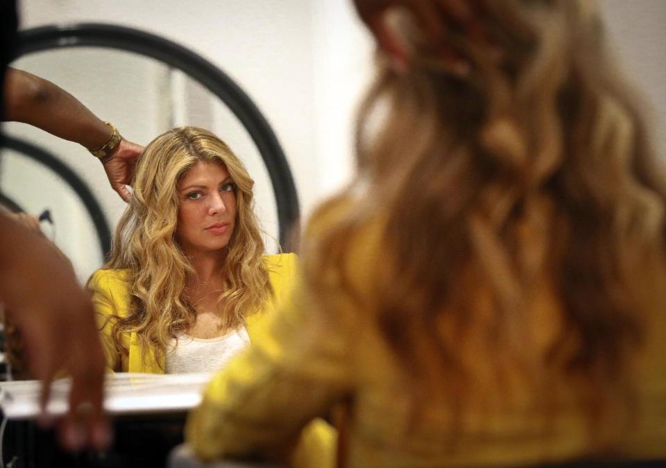 This May 21, 2013 photo shows Alisha Levine with a wavy beach-like hairstyle at Dream Dry salon in New York. When it comes to hair, the grass often seems greener on the other side, but experts say both curly and straight looks require a little work. (AP Photo/Bebeto Matthews)