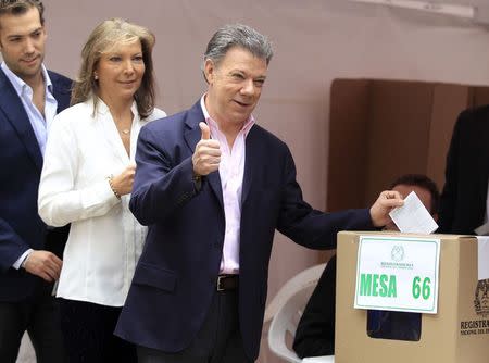 President Juan Manuel Santos gestures before casting his vote as he is accompanied by his wife Maria Clemencia and son Martin in Bogota June 15, 2014. REUTERS/Jaime Saldarriaga
