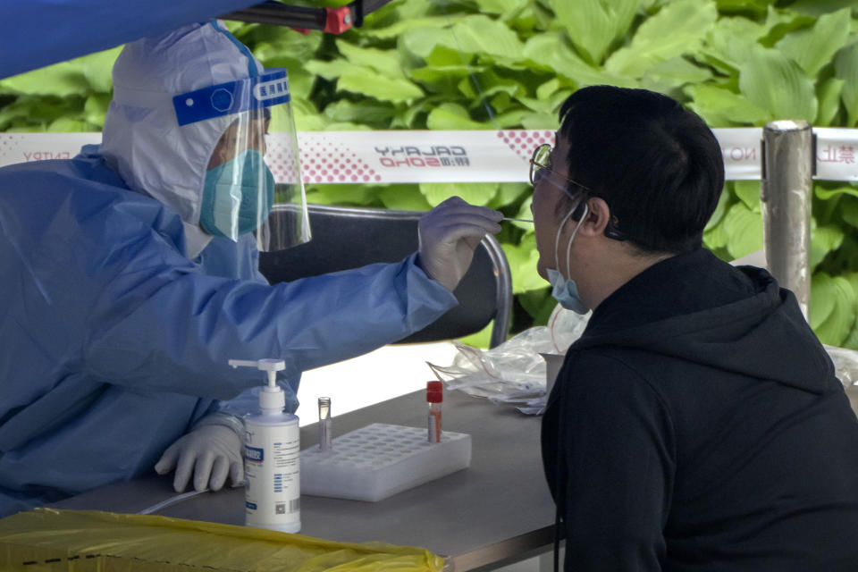 A worker wearing a protective suit swabs a man's throat for a COVID-19 test at a testing site in an office complex in Beijing, Friday, April 29, 2022. While the U.S. and other countries are dropping restrictions and opening - with some health officials even saying the worst is over - China is keeping its international borders largely shut and closing off entire cities with millions of residents to all but essential travel. For the Chinese capital, however, the political stakes are heightened as the ruling party moves toward a crucial national congress. (AP Photo/Mark Schiefelbein)