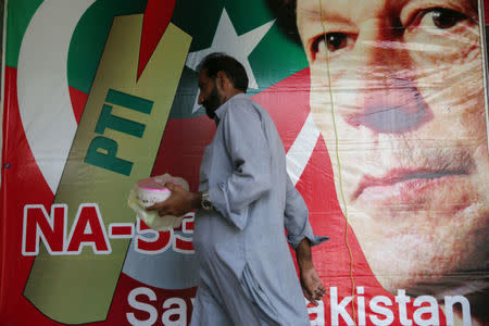 A man walks past an image of cricket star-turned-politician Imran Khan, chairman of Pakistan Tehreek-e-Insaf (PTI) at a market in Islamabad, Pakistan, July 27, 2018. REUTERS/Athit Perawongmetha