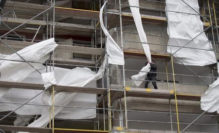 A worker removes parts of a loose covering of a scaffolding as Storm Niklas strikes in Berlin March 31, 2015.REUTERS/Hannibal Hanschke