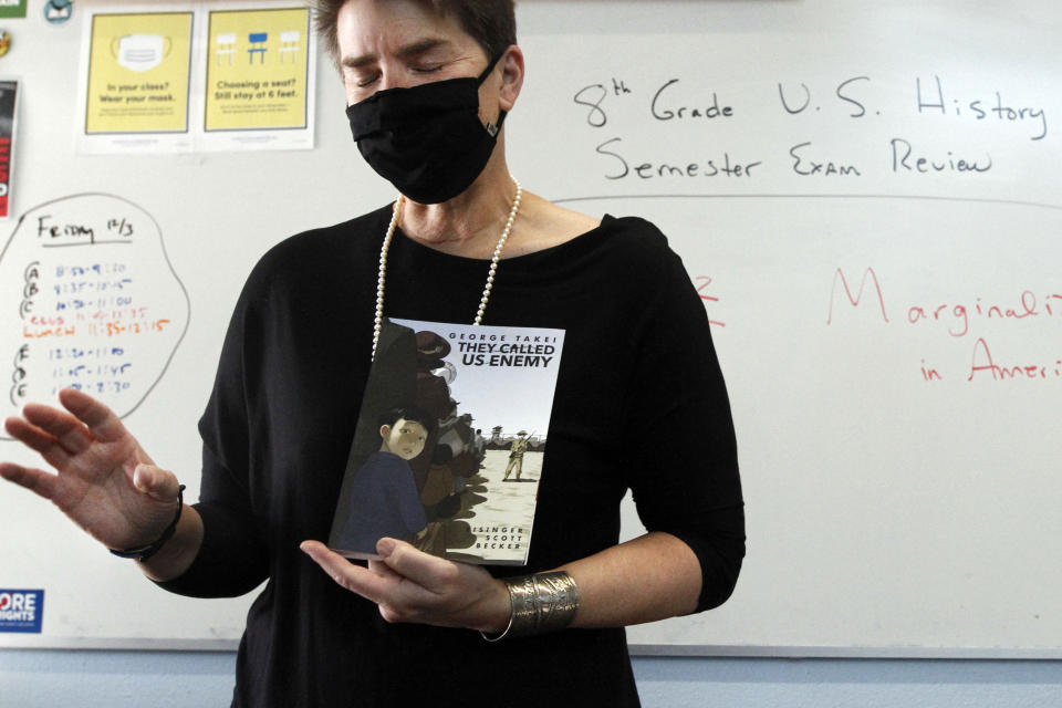 History teacher Wendy Leighton holds a copy of "They Called us Enemy," about the internment of Japanese Americans, while speaking about marginalized with her students at Monte del Sol Charter School, Friday, Dec. 3, 2021, in Santa Fe, N.M. Leighton is one of dozens of educators who helped draft state's proposed changes to the social studies curriculum, including adding the Sept. 11 attacks and the history of LGBTQ rights. It would increase the focus on ethnic studies in a state where 49 percent of the population is Hispanic, and 11 percent is Indigenous. (AP Photo/Cedar Attanasio)