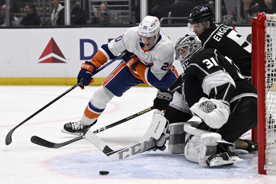 New York Islanders right wing Hudson Fasching (20) shoots a wraparound shot as Los Angeles Kings goaltender David Rittich (31) and defenseman Andreas Englund (5) defend during the first period of an NHL hockey game in Los Angeles, Monday, March 11, 2024. (AP Photo/Alex Gallardo)