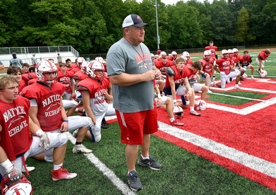 Natick head coach Mark Mortarelli stands with his players during introductions before a scrimmage against Holliston at Holliston High School, Aug. 26, 2022. 