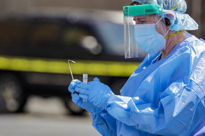 MONTCLAIR, CA - APRIL 14: A public health care worker collects a nasal swab for novel coronavirus testing at a drive-through sample collection event held by San Bernardino County Department of Public Health at Montclair Plaza, Montclair, CA. (Irfan Khan / Los Angeles Times)