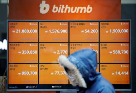 FILE PHOTO: A man walks past an electric board showing exchange rates of various cryptocurrencies at Bithumb cryptocurrencies exchange in Seoul, South Korea, January 11, 2018.  REUTERS/Kim Hong-Ji/File Photo