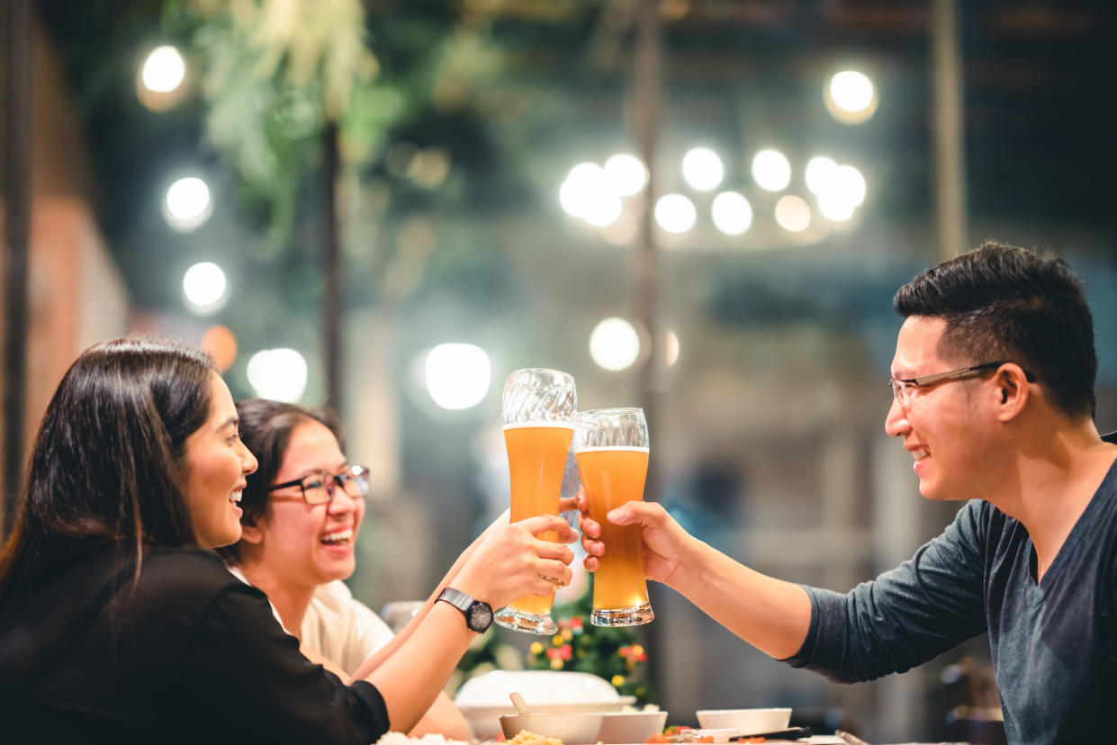 Group of friends cheering with beer, celebrating together at a restaurant. (Photo: Getty)