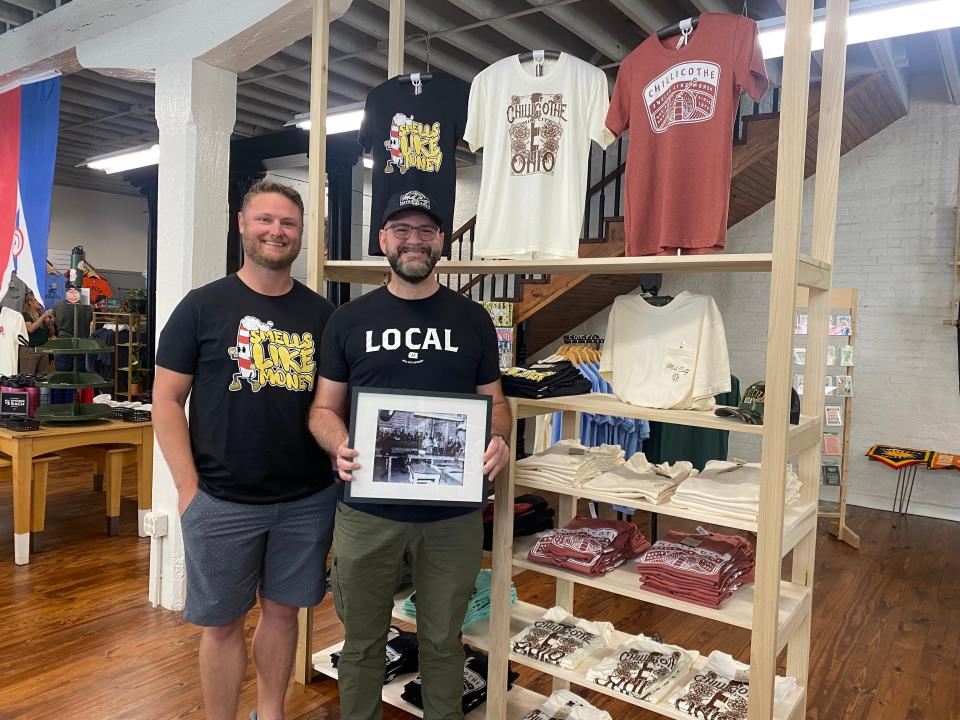 Chad McAllister and Jarrod DePugh of Mill City Apparel celebrated their grand opening on June 30, 2023, at 54 W Water St. DePugh holds a sign of his grandfather's retirement party from the Chillicothe paper mill.