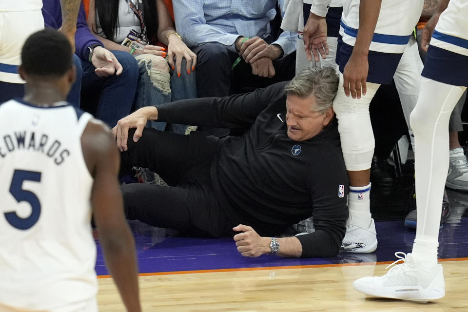 Minnesota Timberwolves head coach Chris Finch holds his knee after colliding with Timberwolves guard Mike Conley during the second half of Game 4 of an NBA basketball first-round playoff series against the Phoenix Suns Sunday, April 28, 2024, in Phoenix. The Timberwolves won 122-116, taking the series 4-0. (AP Photo/Ross D. Franklin)