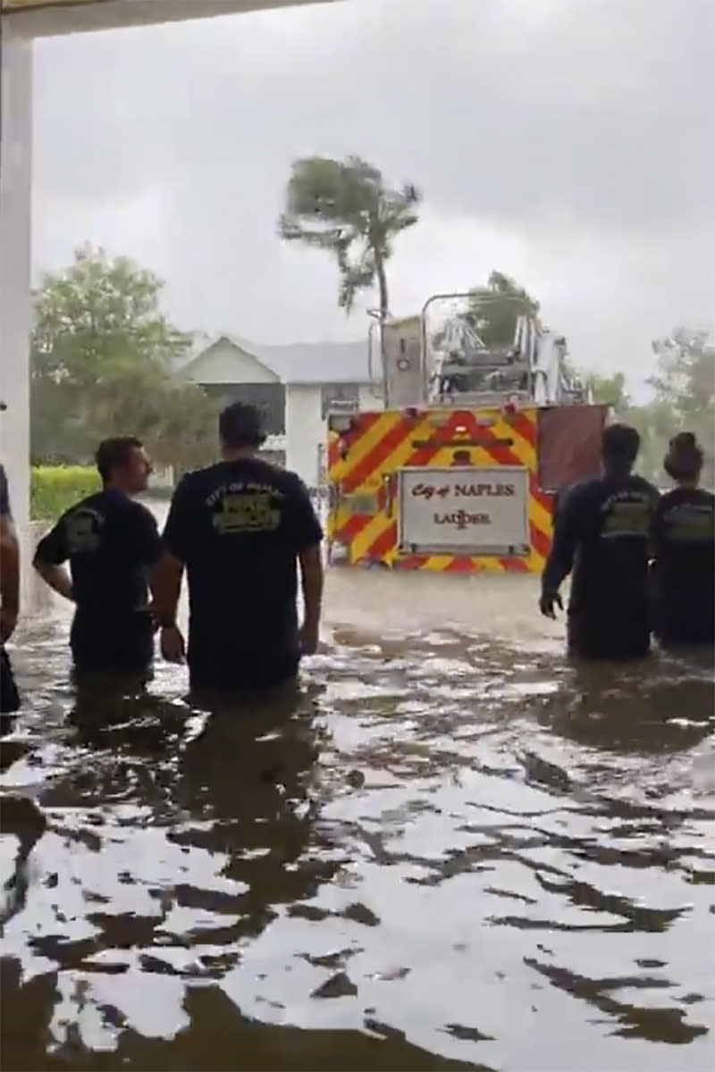 This image provided by the Naples Fire Rescue Department shows firefighters looking out at the firetruck that stands in water from the storm surge from Hurricane Ian on Wednesday, Sept. 28, 2022 in Naples, Fla. Hurricane Ian has made landfall in southwestern Florida as a massive Category 4 storm. (Naples Fire Department via AP)