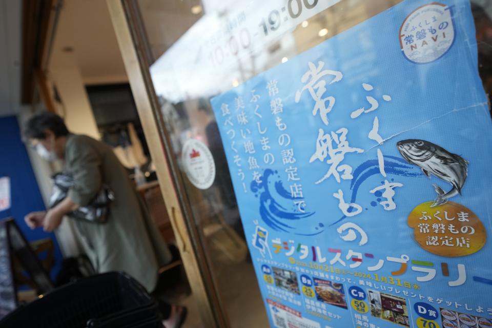 A poster to promote Fukushima seafood is placed on the front door at Sakana Bacca, a seafood retailer, on Oct. 31, 2023, in Tokyo. Fishing communities in Fukushima feared devastating damage to their businesses from the tsunami-wrecked nuclear power plant’s ongoing discharge of treated radioactive wastewater into the sea. Instead, they're seeing increased consumer support as people eat more fish, a movement in part helped by China’s ban on Japanese seafood. (AP Photo/Eugene Hoshiko)