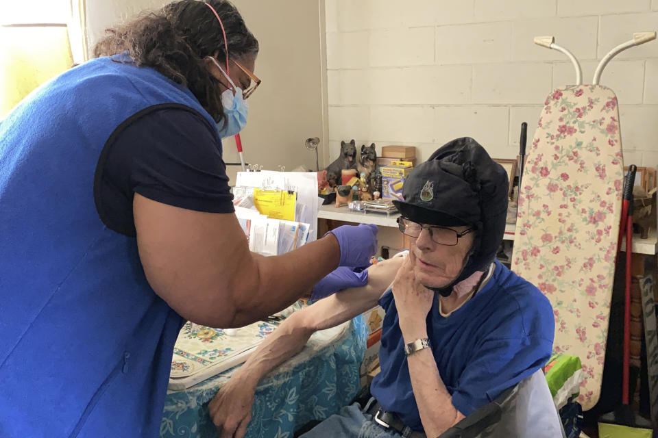 Alameda County nurse Patricia Calloway administers a COVID-19 vaccine to William Brainerd inside his studio apartment in San Leandro, Calif., May 6, 2021. Brainerd, who says he cannot wear a mask because of respiratory issues, has not left his apartment complex since the pandemic began. (AP Photo/Terry Chea)