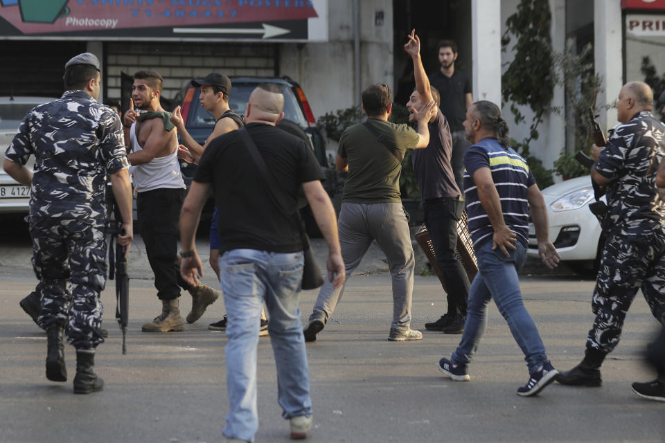 Angry anti-Government protesters scuffle with Lebanese policemen after a supporter of President Michel Aoun opened fire over the heads of protesters in the town of Jal el-Dib, north of Beirut, Lebanon, Wednesday, Nov. 13, 2019. The man opened fire over the heads of protesters in Jal el-Dib Wednesday, the second shooting incident in as many days as tensions rise in Lebanon between supporters and opponents of President Michel Aoun amid nationwide protests. (AP Photo/Hassan Ammar)