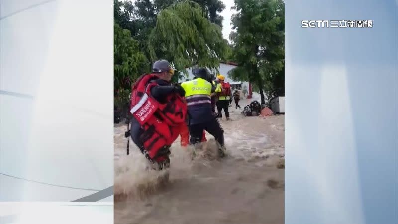 警消人員小心翼翼地走過湍急的水流當中，唯恐被強勁大水沖走。