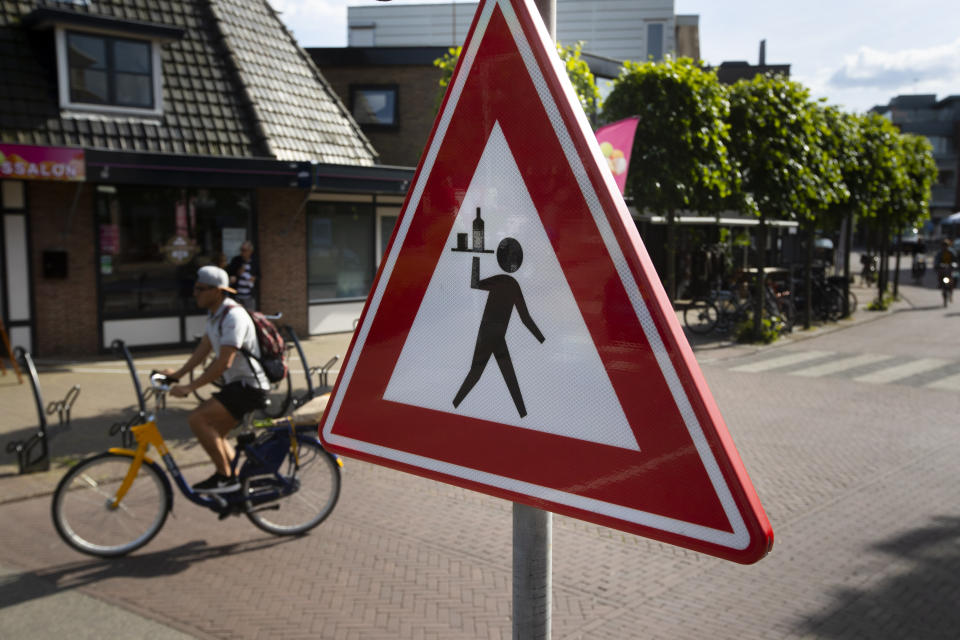 A road sign warns bicyclists and motorists of crossing waiters in the centre of Heiloo, north-western Netherlands, Sunday, May 31, 2020. Bars, restaurants and museum are set to reopen on June 1, and local authorities have relaxed restrictions on terrace space to allow guests to follow social distancing guidelines to curb the spread of The COVID-19 coronavirus. (AP Photo/Peter Dejong)