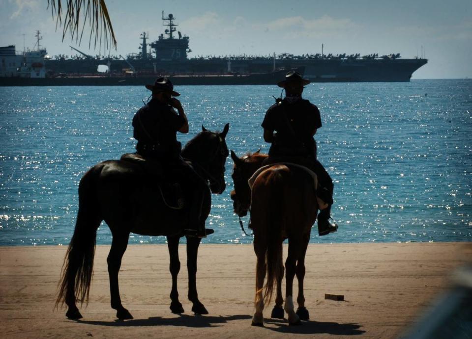 In 2007, Fort Lauderdale Police Officer Duval Madrigal, sits atop his patrol horse, Ebony, and Officer C.J. Smith sits atop his patrol horse, Comanchero, and look out at the view of The USS Truman anchored just off of Fort Lauderdale Beach. The two mounted police officers were on routine patrol of the beach and paused for a moment to enjoy the view.