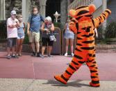 FILE- In this July 11, 2020 file photo, Tigger entertains guests wearing masks as required to attend the official reopening day of the Magic Kingdom at Walt Disney World in Lake Buena Vista, Fla. Walt Disney World announced Wednesday, Oct. 28, 2020, that over 700 actors and singers will be laid off. (Joe Burbank/Orlando Sentinel via AP, File)