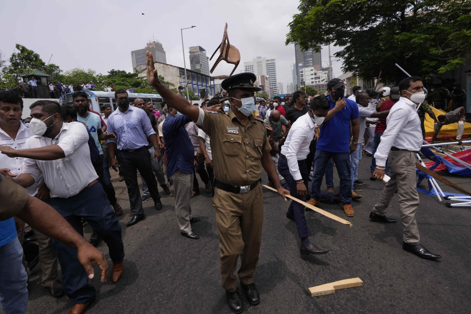 A Sri Lankan police officer tries to control the government supporters during clashes outside prime minister's residence in Colombo, Sri Lanka, Monday, May 9, 2022. Authorities deployed armed troops in the capital Colombo on Monday hours after government supporters attacked protesters who have been camped outside the offices of the country's president and prime minster, as trade unions began a “Week of Protests” demanding the government change and its president to step down over the country’s worst economic crisis in memory. (AP Photo/Eranga Jayawardena)