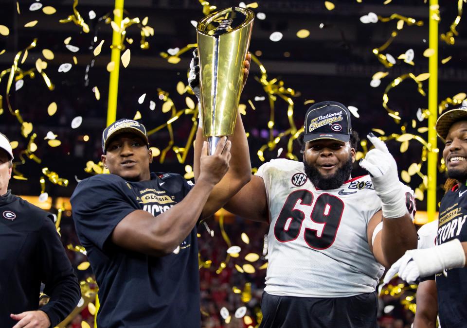 Jan 10, 2022; Indianapolis, IN, USA; Georgia Bulldogs running back Zamir White (left) and offensive lineman Jamaree Salyer (69) celebrate with the trophy after defeating the Alabama Crimson Tide in the 2022 CFP college football national championship game at Lucas Oil Stadium. Mark J. Rebilas-USA TODAY Sports