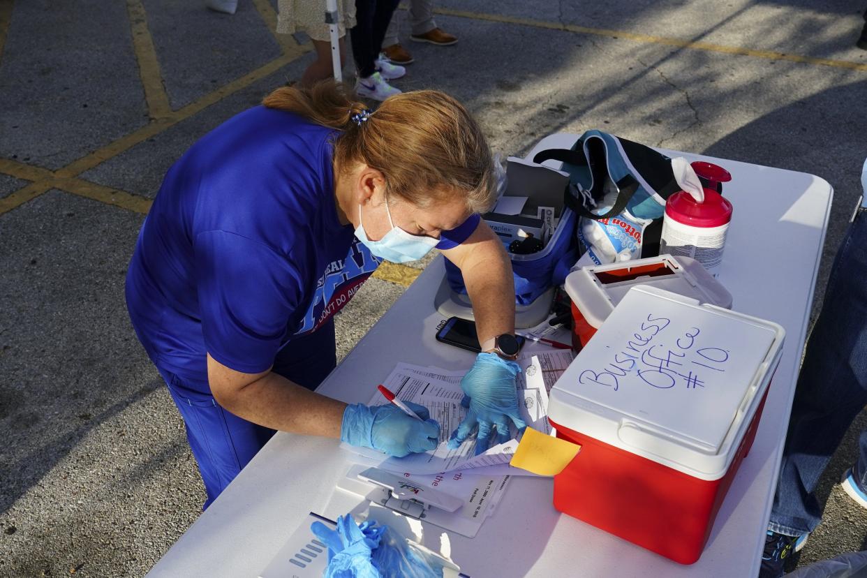 Registered nurse Dalma Velasco fills out a child's vaccine card on Nov. 10 at a vaccine clinic in Brownsville. This year Texas cut $1 million from a $20 million program that helps get more people trained as nurses.