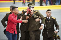 In this photo released by China's Xinhua News Agency, an uniformed official bleeds from the head following an incident during a speech by Venezuela's President Nicolas Maduro in Caracas, Venezuela, Saturday, Aug. 4, 2018. Drones armed with explosives detonated near Venezuelan President Nicolas Maduro as he gave a speech to hundreds of soldiers in Caracas on Saturday but the socialist leader was unharmed, according to the government. (Xinhua via AP)