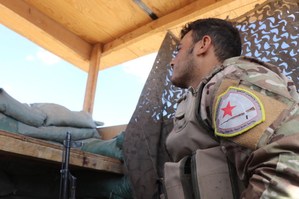 FILE - In this Monday, Oct. 7, 2019 file photo, a fighter from the U.S.-backed Kurdish-led Syrian Democratic Forces, SDF, stands guard inside a post where U.S. troops were based, in Tal Abyad town, at the Syrian-Turkish border, Syria. The region of northeastern Syria, where the Turkish president intends to launch an operation to carve out a safe zone, is one of the most combustible in Syria’s long-running civil war. A U.S. troop withdrawal and Turkish assault on the area risks re-igniting fighting in a corner of Syria only recently stabilized and where sleeper cells of the Islamic State group continue to operate. (AP Photo, File)