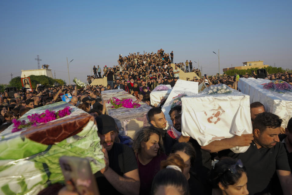 Friends and relatives attend the funeral of people who died in a fire during a wedding ceremony in Hamdaniya, Iraq, Wednesday, Oct. 27, 2023. A fire that raced through a hall hosting a Christian wedding in northern Iraq has killed around 100 people and injured 150 others, and authorities warn the death toll could rise. (AP Photo/Hadi Mizban