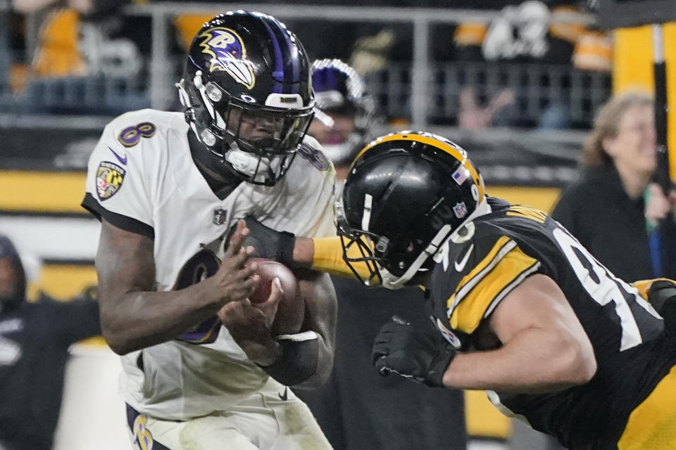 Baltimore Ravens quarterback Lamar Jackson (8) scrambles as Pittsburgh Steelers outside linebacker T.J. Watt (90) swats at the ball during the second half of an NFL football game, Sunday, Dec. 5, 2021, in Pittsburgh. (AP Photo/Gene J. Puskar)