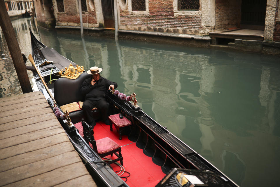 A gondolier talks on his smartphone as he waits for clients in Venice, Saturday, Feb. 29, 2020. A U.S. government advisory urging Americans to reconsider travel to Italy due to the spread of a new virus is the "final blow" to the nation's tourism industry, the head of Italy's hotel federation said Saturday. Venice, which was nearing recovery in the Carnival season following a tourist lull after record flooding in November, saw bookings drop immediately after regional officials canceled the final two days of celebrations this week, unprecedented in modern times. (AP Photo/Francisco Seco)