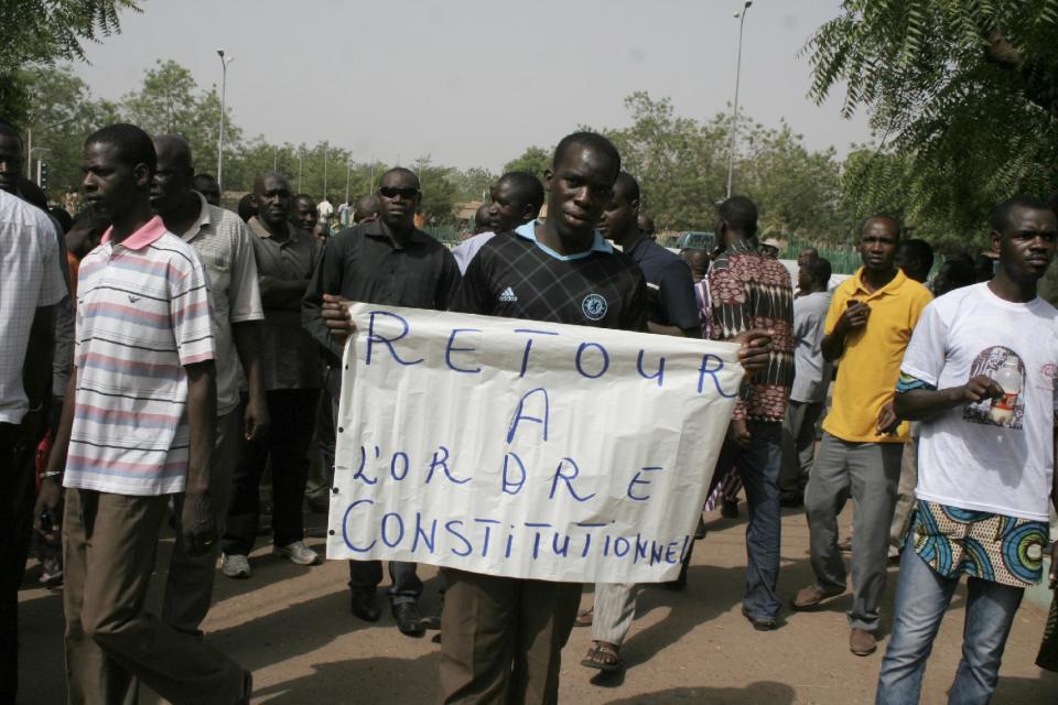 A man carries a sign reading 'Return to constitutional order,' as people gather in protest against the recent military coup, in Bamako, Mali Monday, March 26, 2012. About a thousand demonstrators protested Monday in Mali's capital to demand a return to constitutional order days after mutinous soldiers claimed power in a coup.(AP Photo/Harouna Traore)