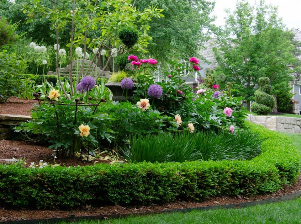 Peonies and allium plants will delight visitors to this groomed garden.