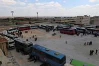 People, who were evacuated from the two rebel-besieged Shi'ite villages of al-Foua and Kefraya, stand near buses at insurgent-held al-Rashideen, Aleppo province, Syria April 19, 2017. REUTERS/Ammar Abdullah