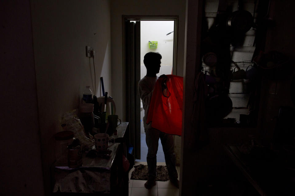 Shamshu, a member of Myanmar's long-persecuted Rohingya minority, changes clothes upon returning home in peninsular Malaysia, Monday, March 4, 2019. Shamshu is part of an invisible workforce made up of millions of poor laborers, including many who face exploitation and abuse, within Malaysia and neighboring Indonesia. Together, the two countries produce an estimated 85 percent of the world's $65 billion palm oil supply. (AP Photo/Gemunu Amarasinghe)