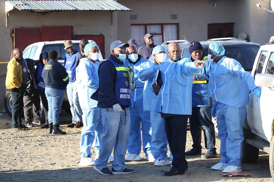 Police and investigators put on protective clothing before going into a township pub in South Africa's southern city of East London on June 26, 2022, after 20 teenagers died. - At least 20 teenagers, the youngest aged just 13 years, have died at a township pub in South Africa's southern city of East London, but the cause of the deaths is still unclear. Crowds of people including parents whose children were missing gathered outside the tavern located along a street in a residential township as mortuary vehicles collected bodies, according to an AFP correspondent.