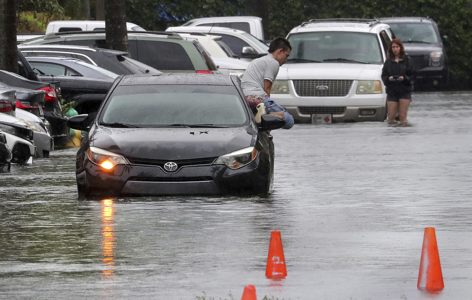 A driver climbs out of his stalled car after he tried to move it to higher ground from the flooded parking lot at the Beachwalk at Sheridan Apartments in Dania Beach, Fla., on Saturday, June 4, 2022. (Mike Stocker/South Florida Sun-Sentinel via AP)