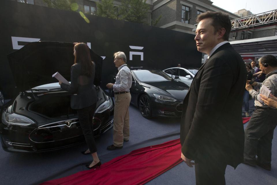 Tesla Motors CEO Elon Musk, right, looks on as a set of Tesla Model S sedans are delivered to its first customers in China at an event in Beijing, China, Tuesday, April 22, 2014. Tesla Motors delivered its first eight electric sedans to customers in China on Tuesday and Musk said the company will build a nationwide network of charging stations and service centers as fast as it can. (AP Photo/Ng Han Guan)