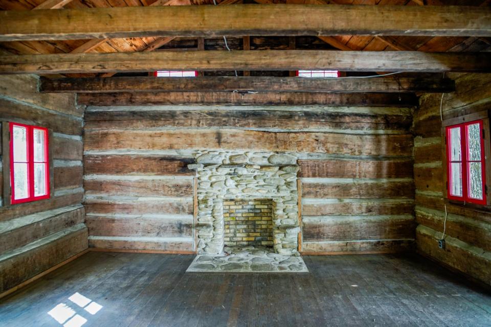 Inside a cabin with a fireplace in the middle and red windows on either side