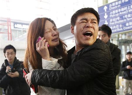 A relative (woman in white) of a passenger onboard Malaysia Airlines flight MH370 cries as she talks on her mobile phone at the Beijing Capital International Airport March 8, 2014. REUTERS/Kim Kyung-Hoon