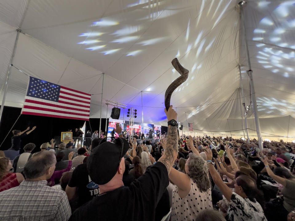 FILE - A man holds up a shofar as the audience prays inside a tent during the ReAwaken America Tour at Cornerstone Church in Batavia, N.Y., Aug. 12, 2022. The instrument, used in some Jewish worship services, has been adopted by the far right, and several people blew the horns to open the conference. (AP Photo/Carolyn Kaster, File)
