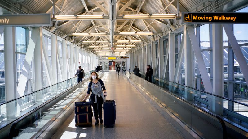 FILE PHOTO: A woman wears a face mask as she exits one of the terminals at the John F. Kennedy International Airport in New York