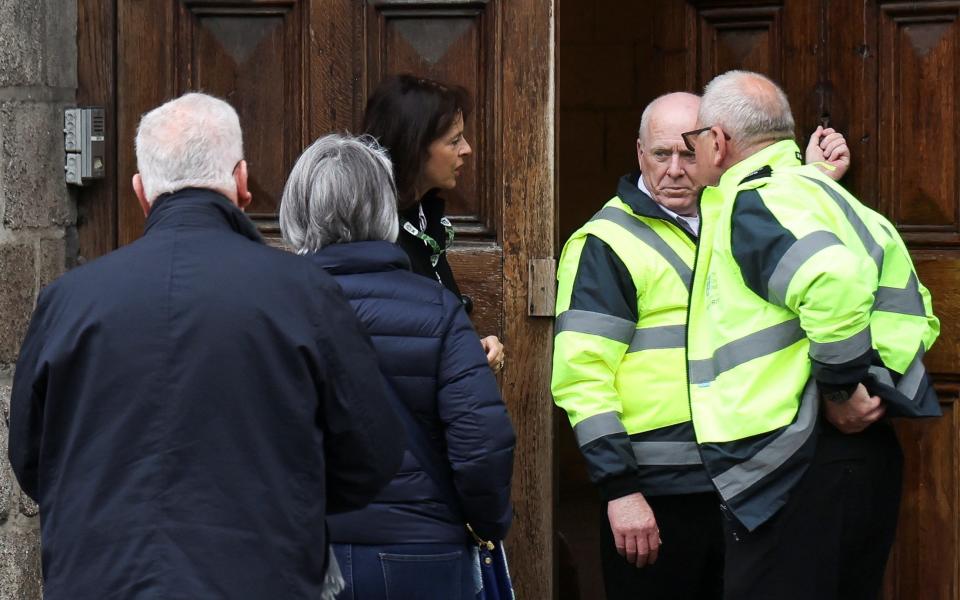 A woman talks with security guards outside the Trinity College, which is currently closed due to a protest by students in support of Palestinians in Gaza