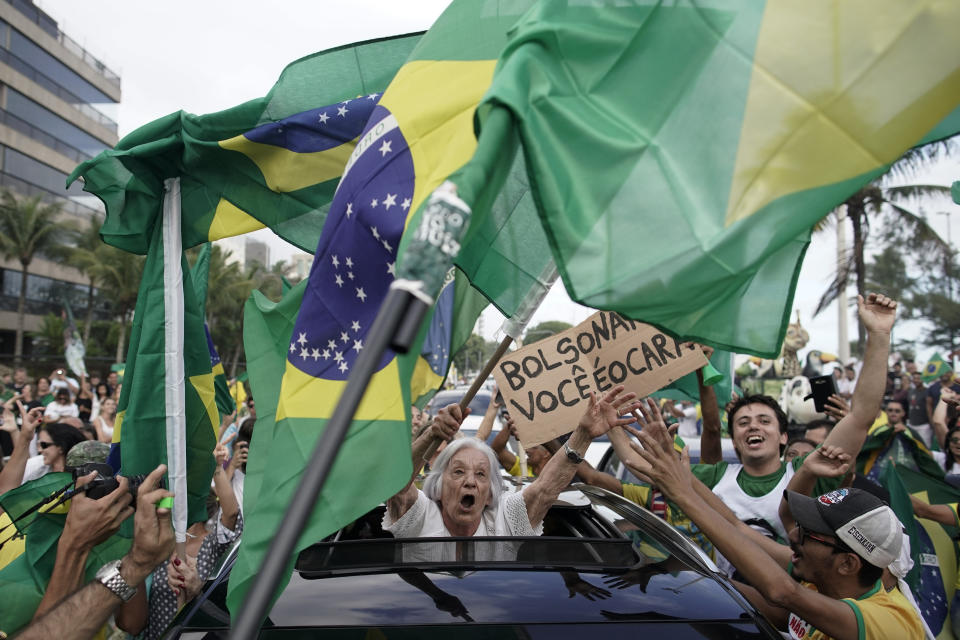 Supporters of Brazilian presidential candidate Jair Bolsonaro cheer as they gather outside his residence in Rio de Janeiro, Brazil, Sunday, Oct. 28, 2018, during the country's presidential runoff election. Brazilians on Sunday were weighing their hunger for radical change against fears that Bolsonaro, the presidential front-runner, could threaten democracy as they cast ballots in the culmination of a bitter campaign that split many families and was frequently marred by violence. (AP Photo/Leo Correa)