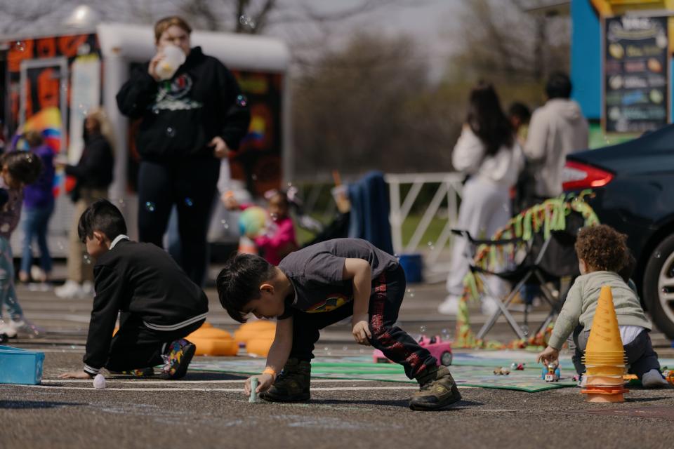 Children blowing bubbles and drawing on the concrete with chalk.