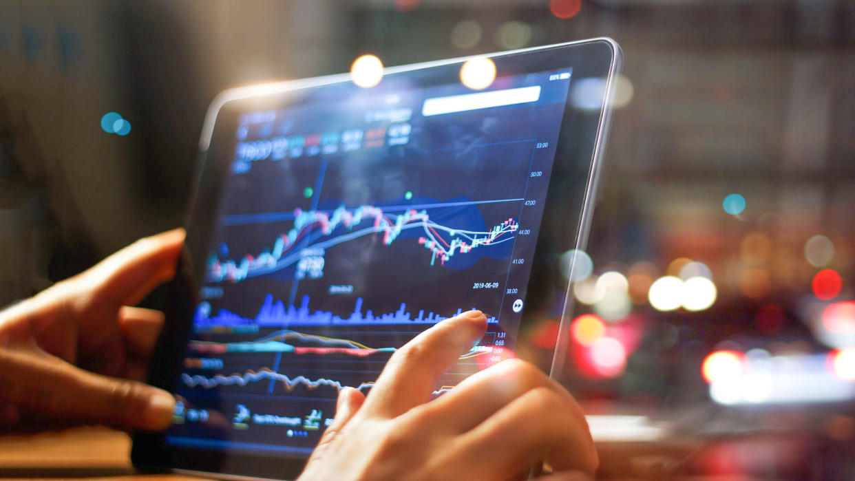 Businessman checking stock market data on tablet on night background.