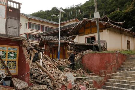 A man walks through the debris of a building that was damaged during an earthquake next to a temple compound in Jiuzhaigou, Sichuan province, China, August 10, 2017. REUTERS/Thomas Peter