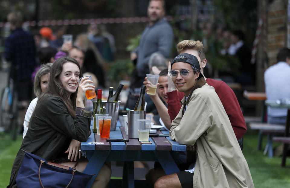 People enjoy their drinks at The Black Lion pub in London, Saturday, July 4, 2020. England is embarking on perhaps its biggest lockdown easing yet as pubs and restaurants have the right to reopen for the first time in more than three months. In addition to the reopening of much of the hospitality sector, couples can tie the knot once again, while many of those who have had enough of their lockdown hair can finally get a trim. (AP Photo/Frank Augstein)