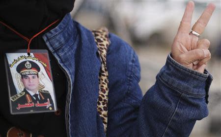 A supporter of Egypt's army chief Field Marshal Abdel Fattah al-Sisi wears an image of him around her neck as she rallies outside a police academy, where the trial of ousted Egyptian President Mohamed Mursi and members of the Muslim Brotherhood is due to take place, on the outskirts of Cairo, February 16, 2014. REUTERS/Amr Abdallah Dalsh